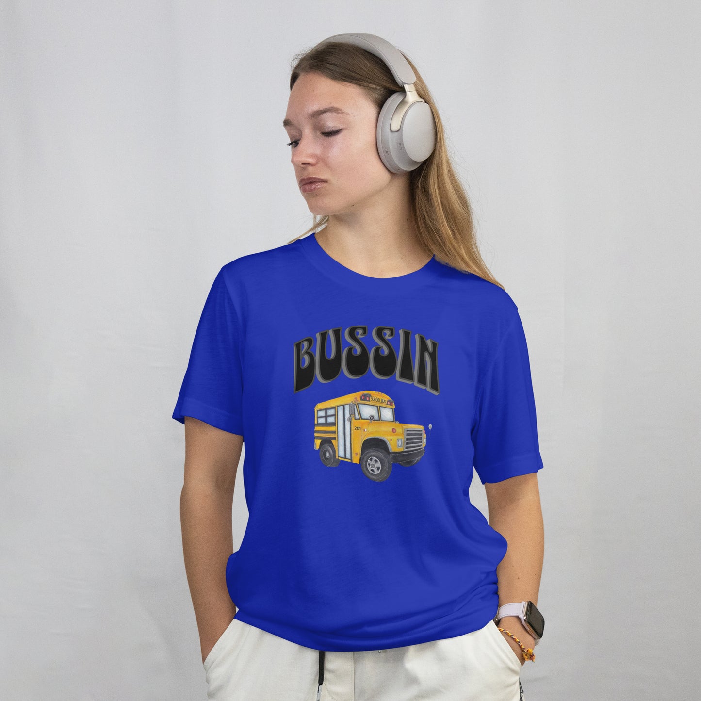 Person wearing a blue t-shirt with a hand drawn school bus and the word 'BUSSIN' on a plain background