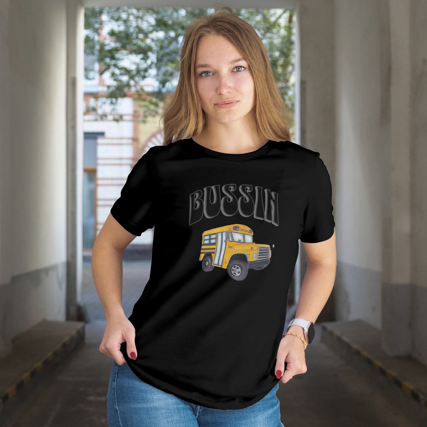 Person wearing a black t-shirt with a hand-drawn school bus and text in an indoor setting